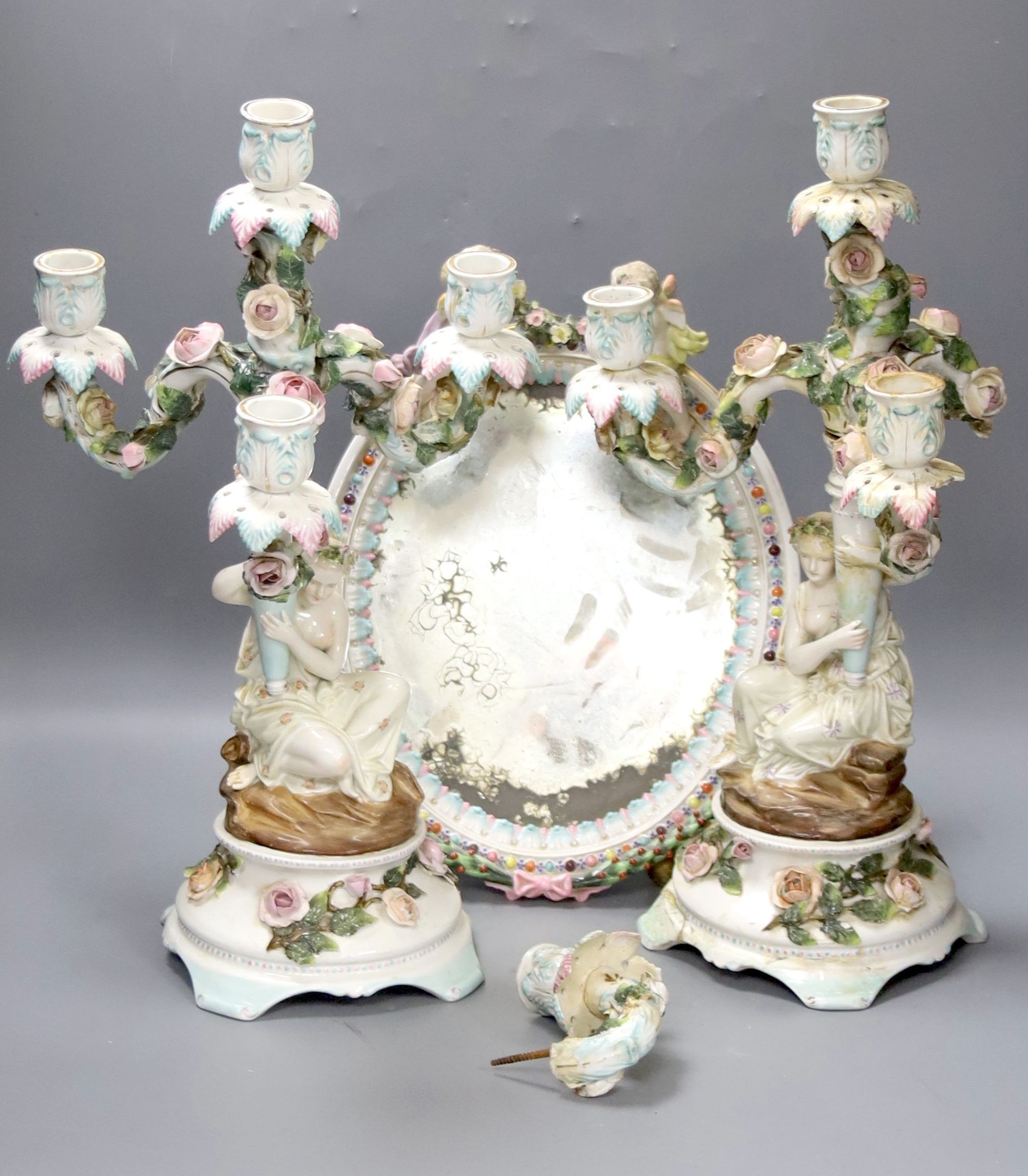 A pair of 19th century German porcelain three branch candelabra (a.f.) and an oval porcelain framed wall mirror (3)